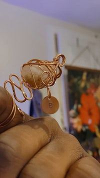 a person holding a copper ring with a stone in it