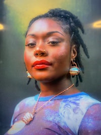 a woman with dreadlocks in front of a poster